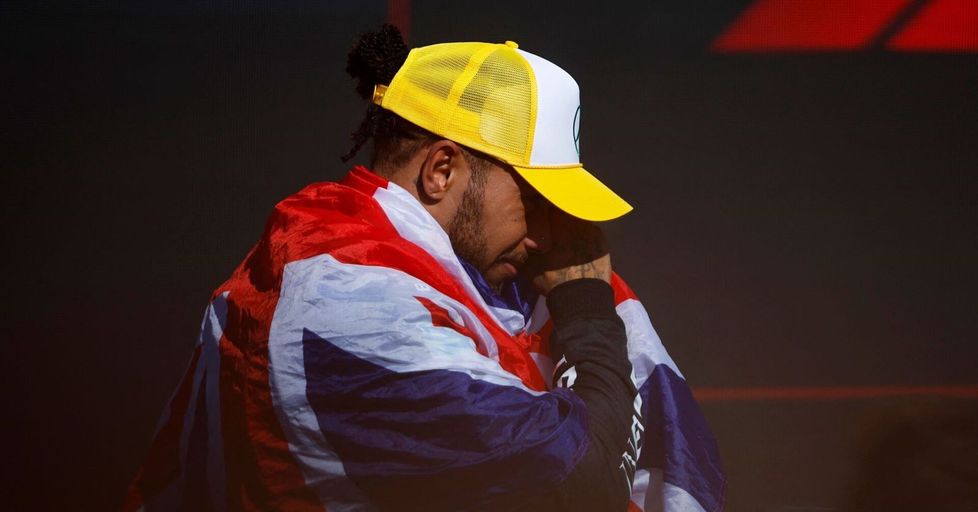 Lewis Hamilton, eine britische Flagge um seine Schultern, steht am Siegerpodium in Silverstone und weint.