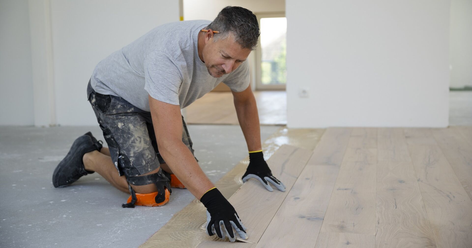 Ein Handwerker verlegt in einer Wohnung einen Boden.