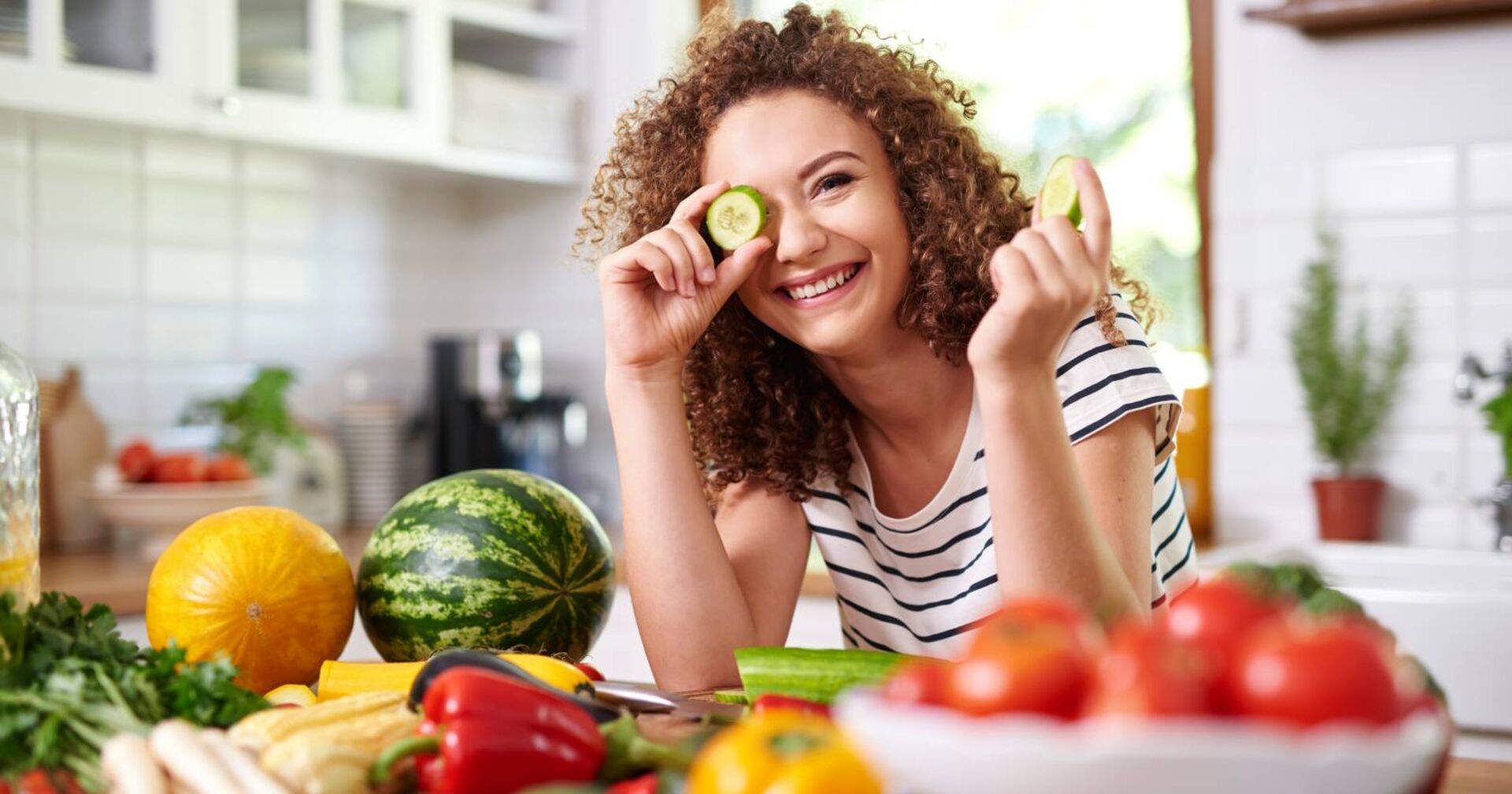 Frau mit lockigem Haar beim kochen von veganem Essen