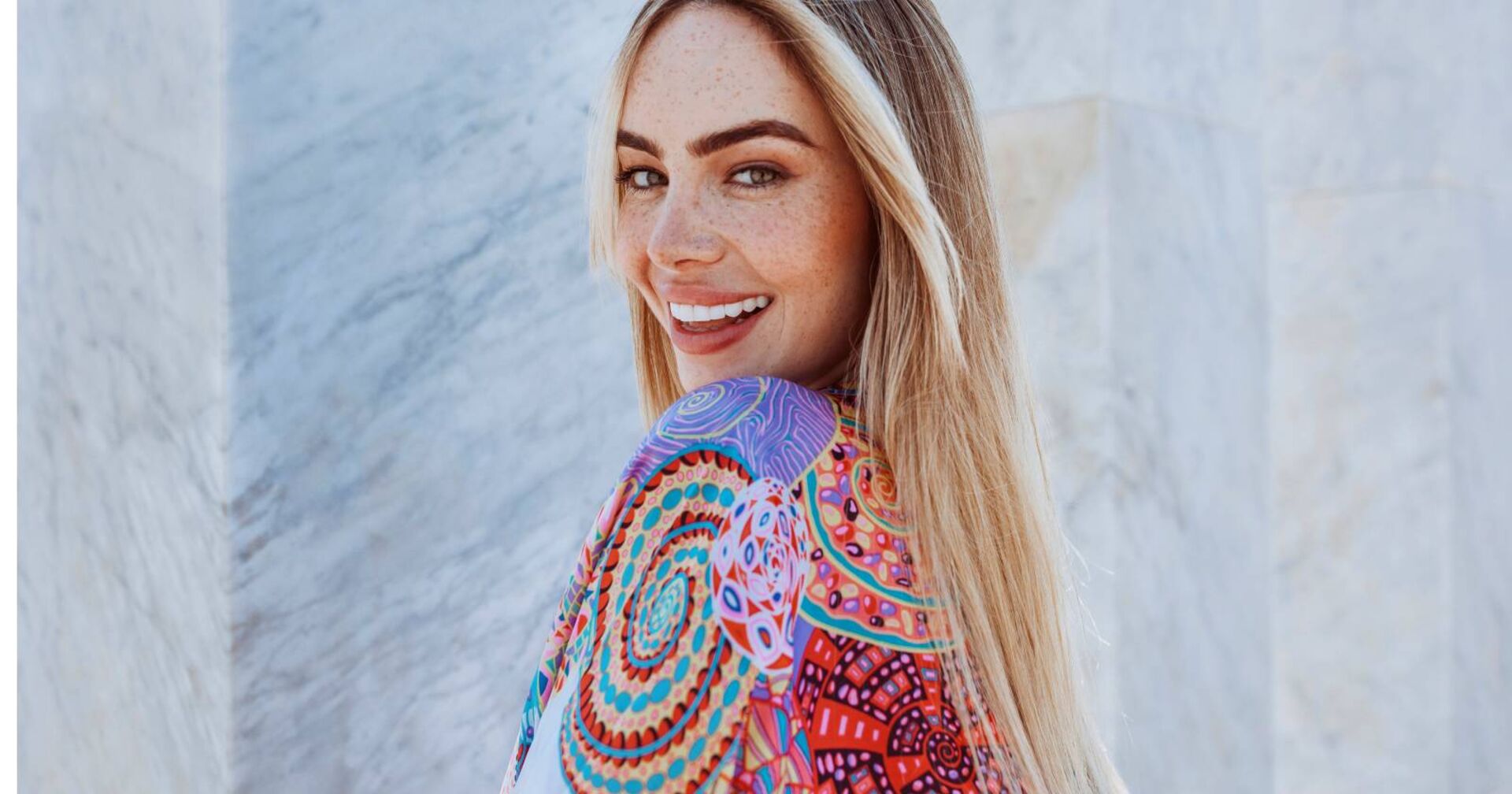 Blonde Frau im sommerlichem bunten Kleid lächelt