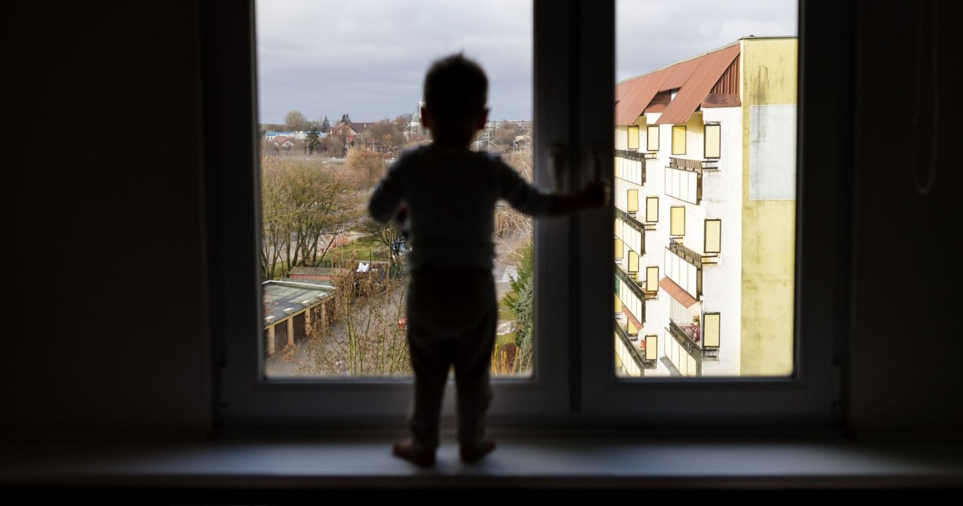 Ein Junge steht an einem Fenster.