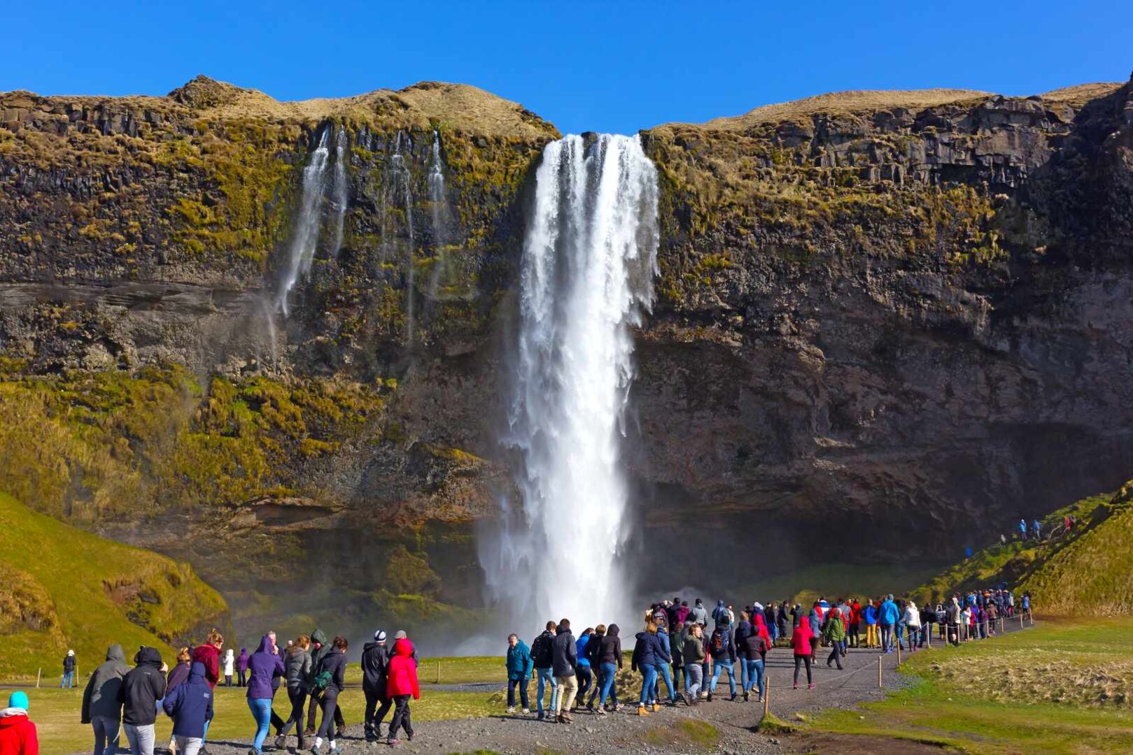 Viele Touristen vor einem Wasserfall in Island.