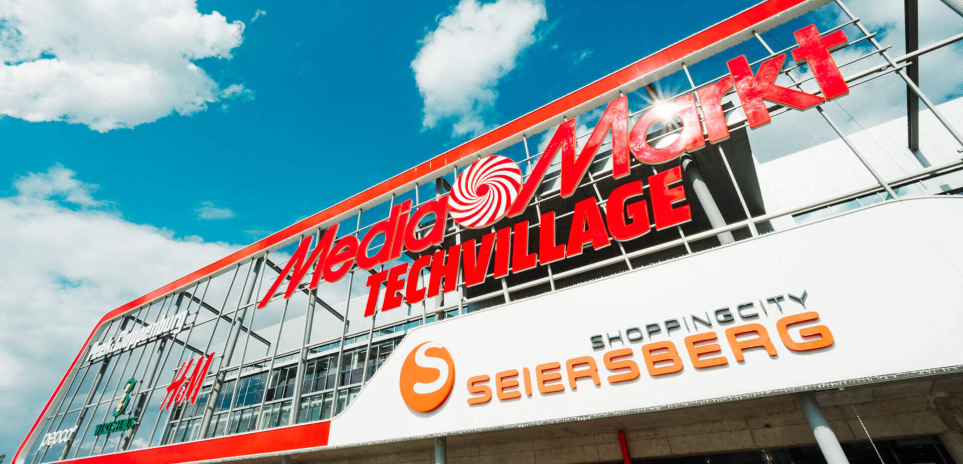 Roter Schriftzug eines Ladens, darüber ein blauer Himmel