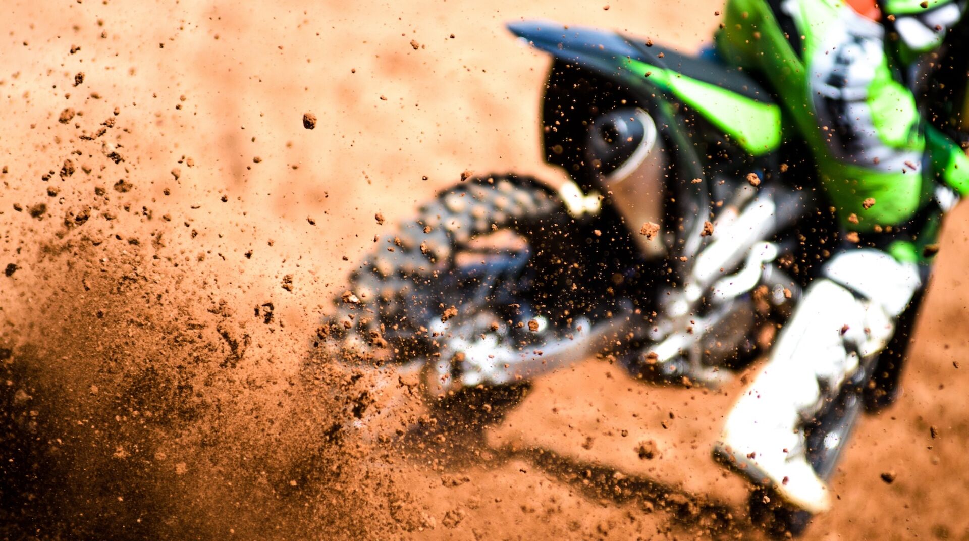 Motocross-Fahrer wirbelt mit den Reifen Schmutz auf