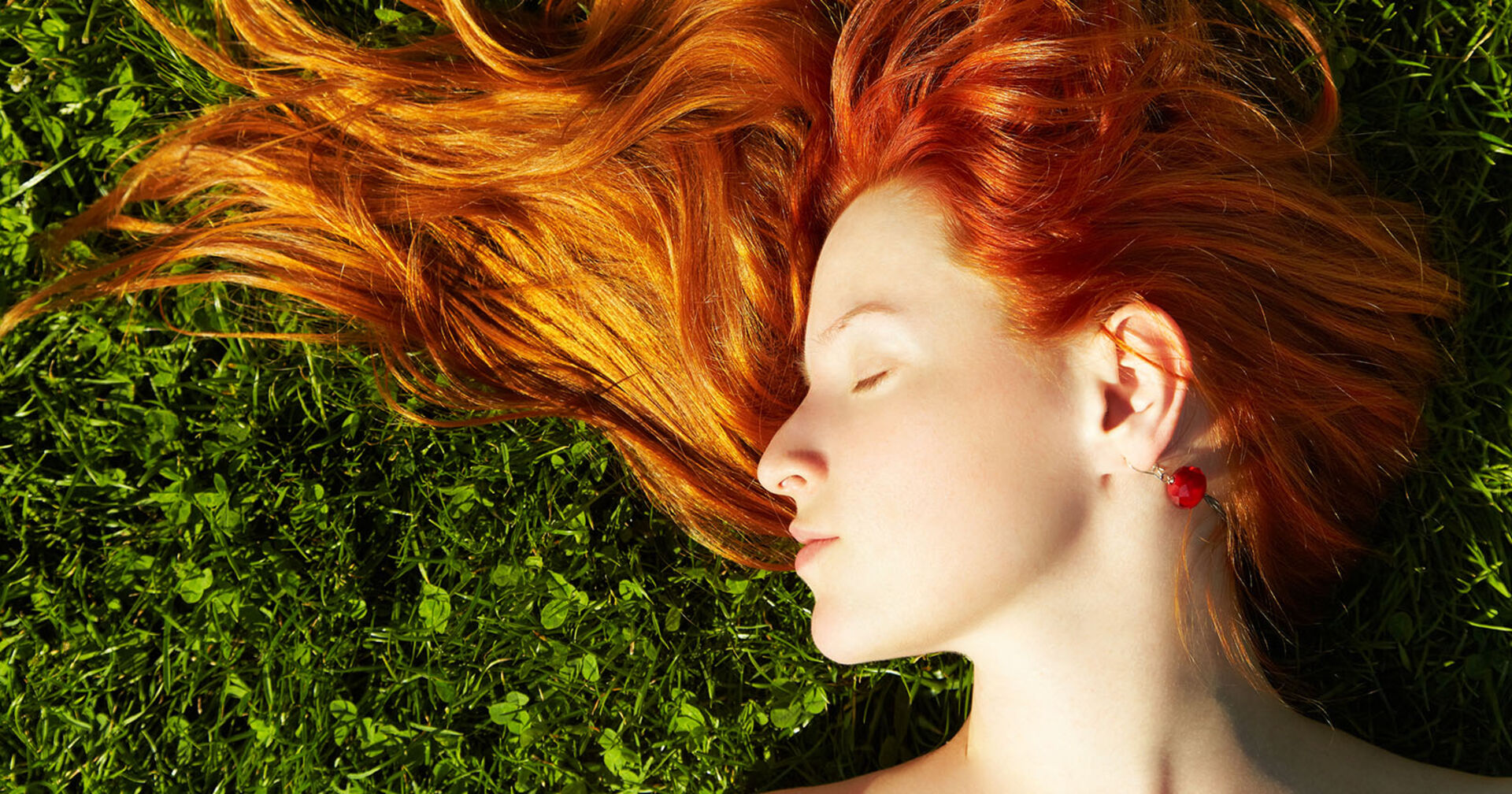 Frau mit roten Haaren liegt im Gras | Credit: iStock.com/Bakharev