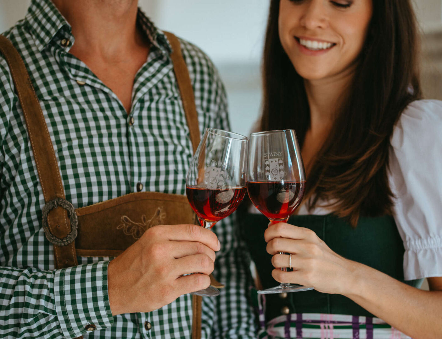 Mann und Frau in Tracht stoßen mit einem Wein an