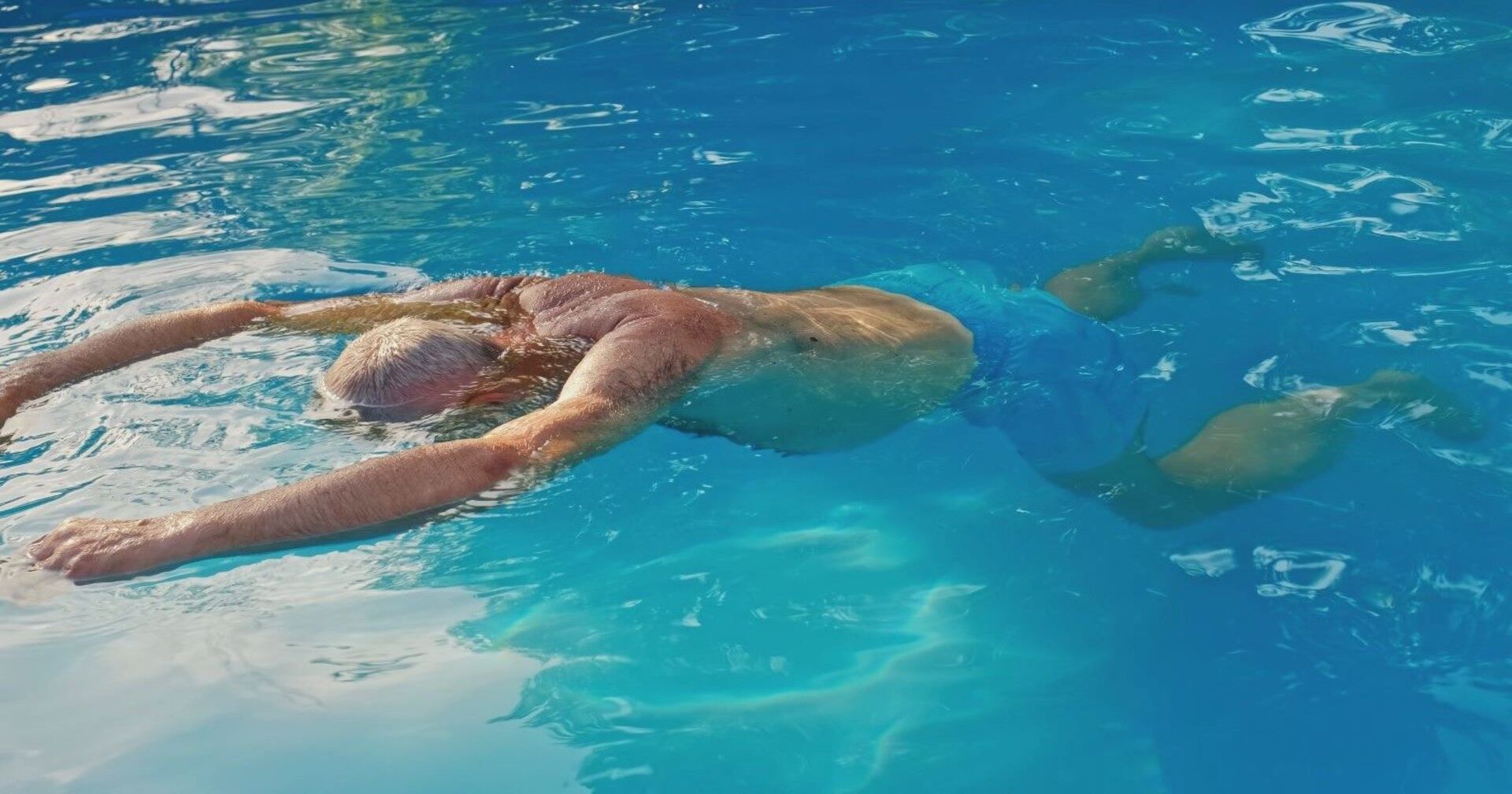 Ein älterer Mann treibt reglos in einem Wasserbecken.