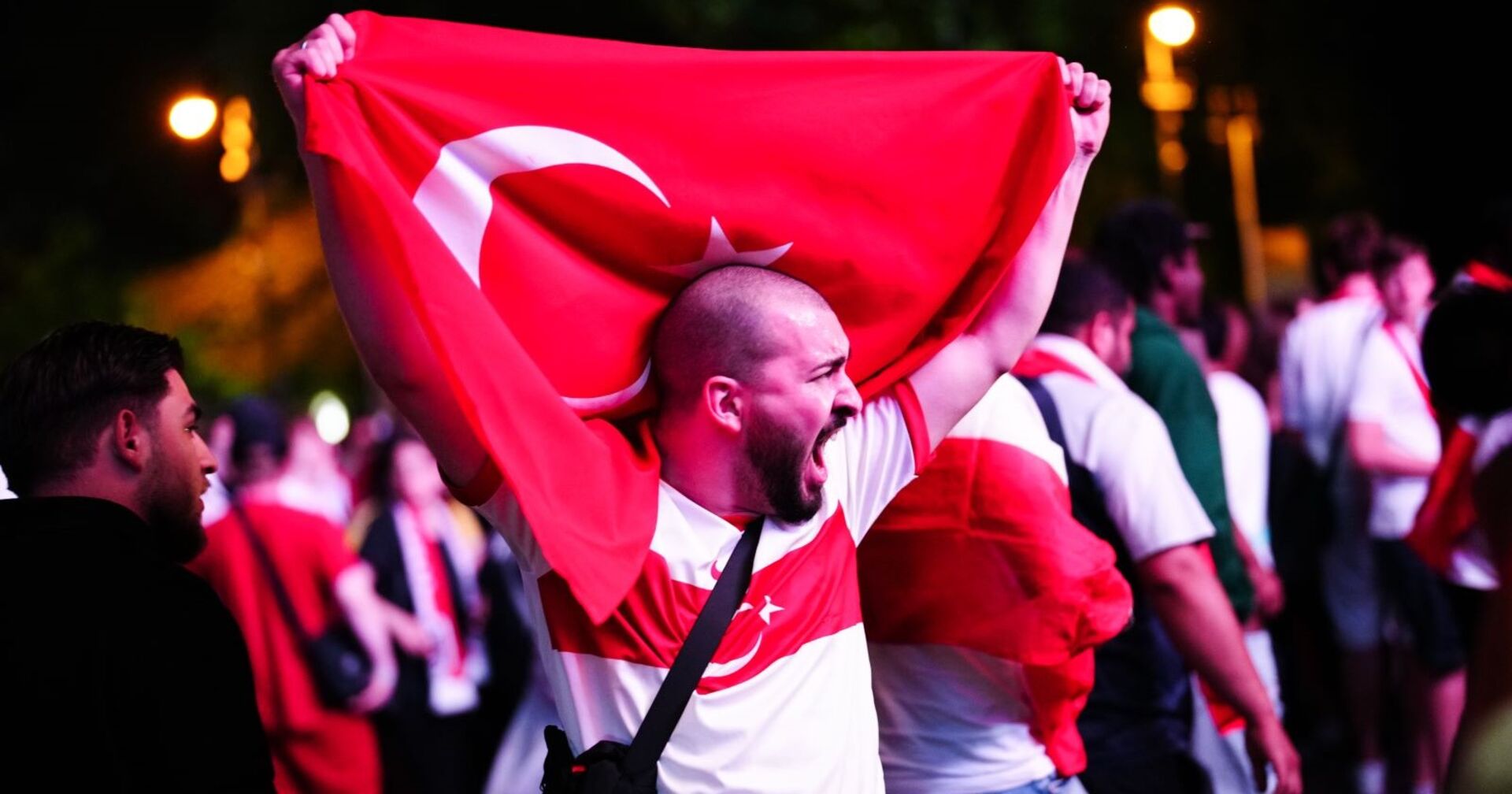 Ein türkischer Fan hält jubelnd die Flagge der Türkei in die Luft