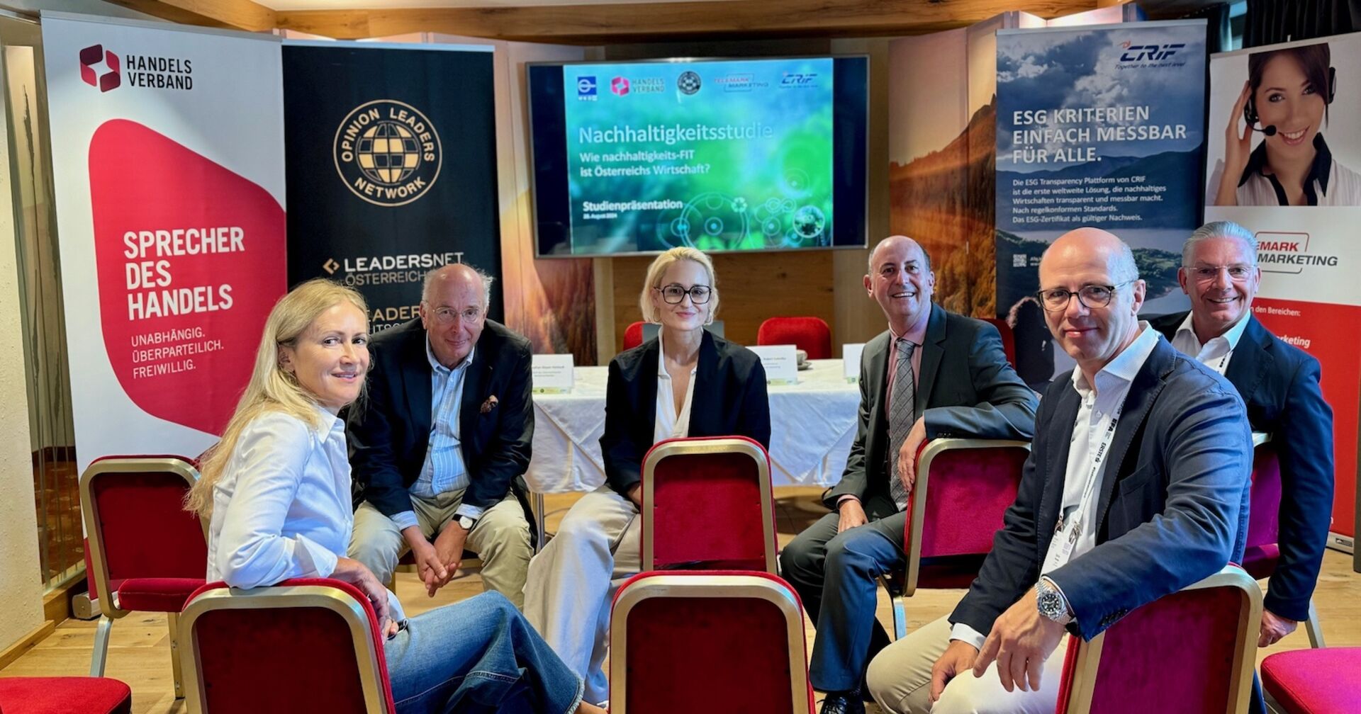 Gruppe von Menschen dreht sich auf Sesseln sitzend zum Fotografen um