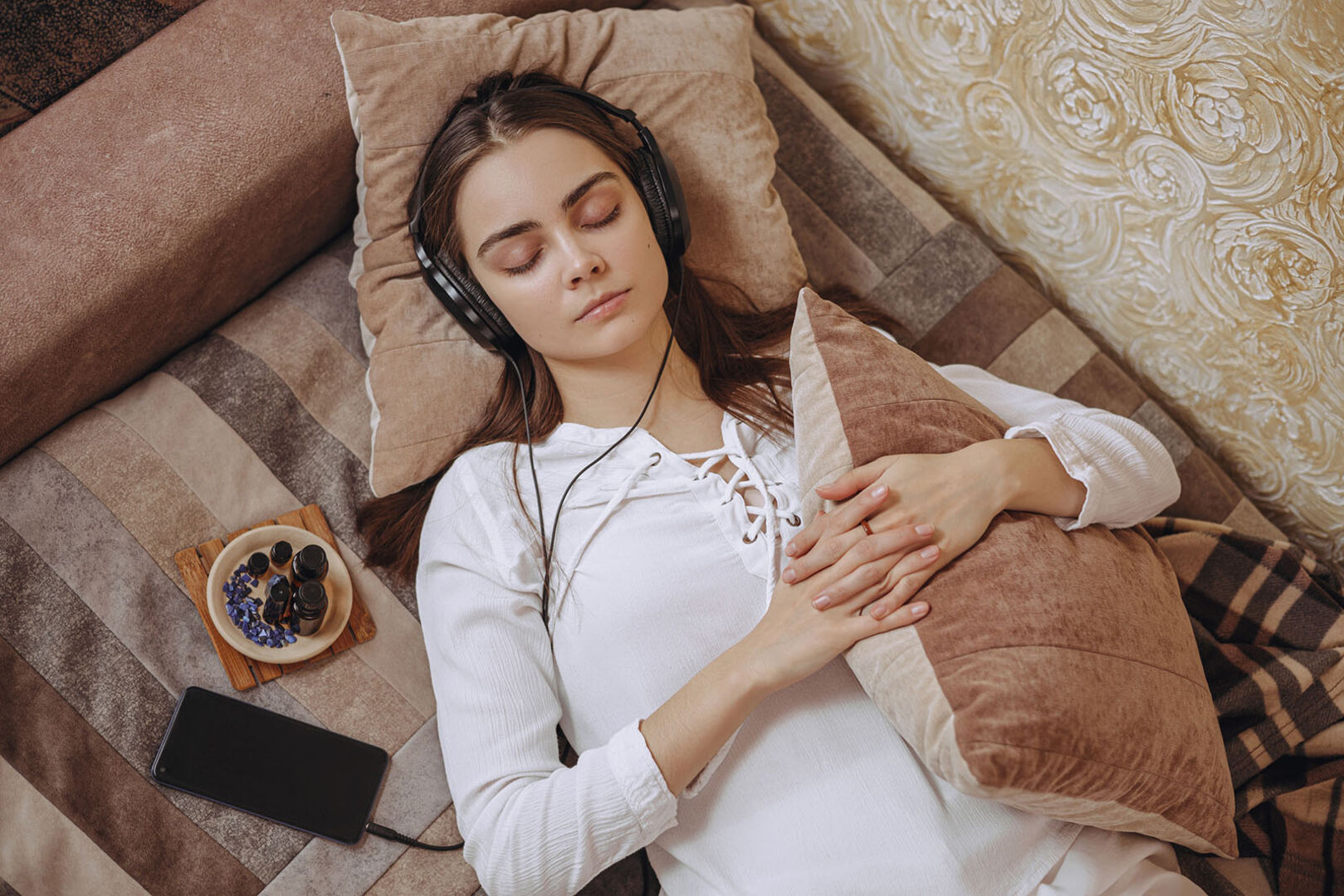 Frau liegt mit Kopfhörern auf der Couch | Credit: iStock.com/Dzmitry Dzmitryieu