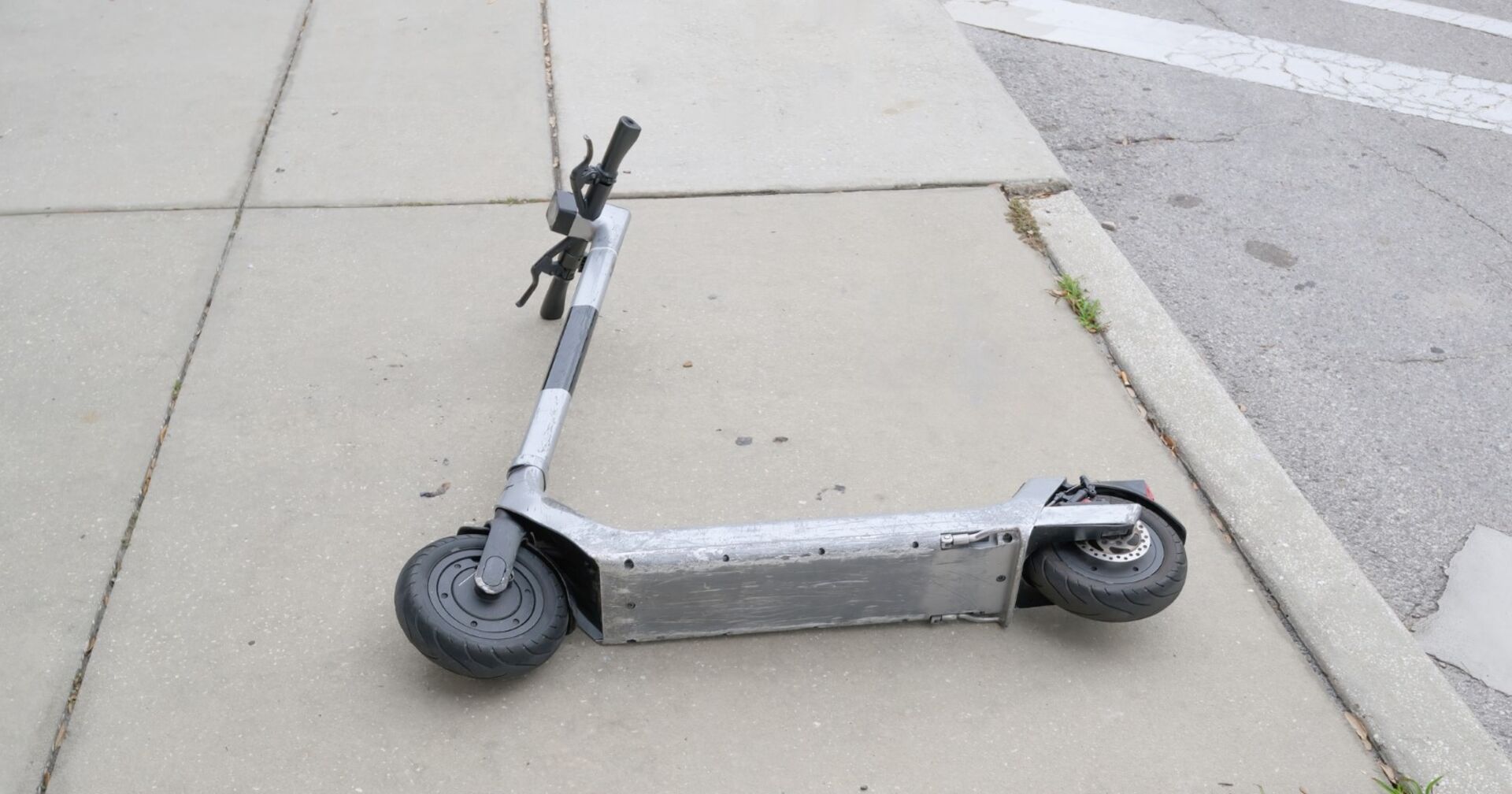 Grauer Elektro-Roller liegt auf Straße