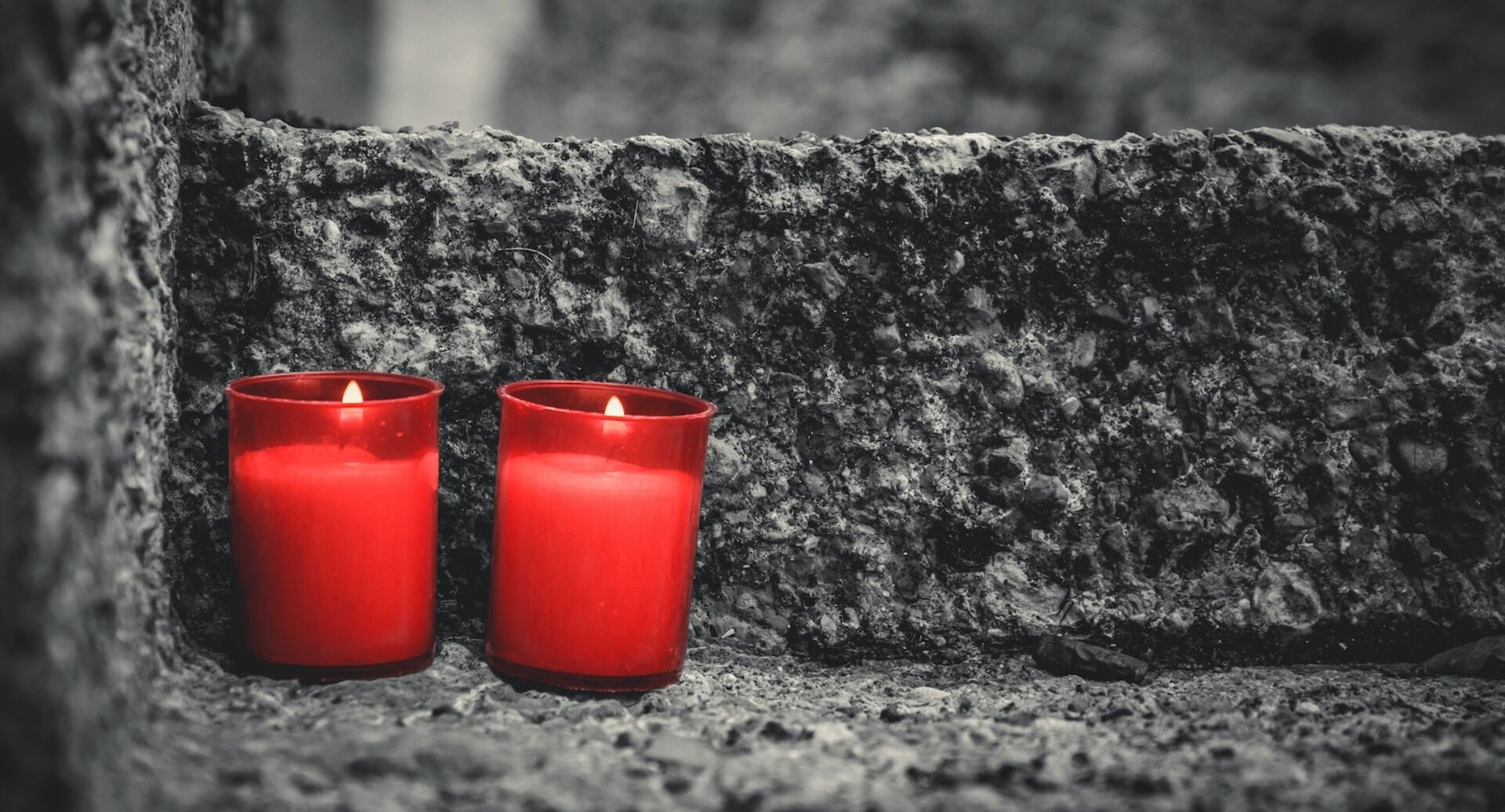 zwei rote Kerzen am Grabstein