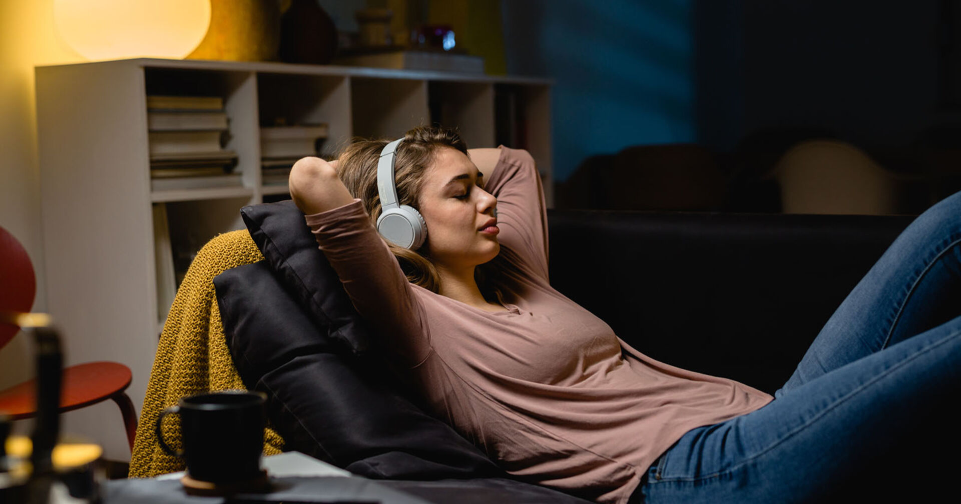 Frau liegt auf der Couch mit Kopfhörern | Credit: iStock.com/Dejan_Dundjerski