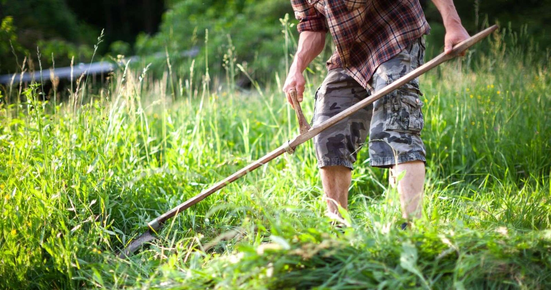 Ein Landwirt mäht das Gras mit einer Sense.
