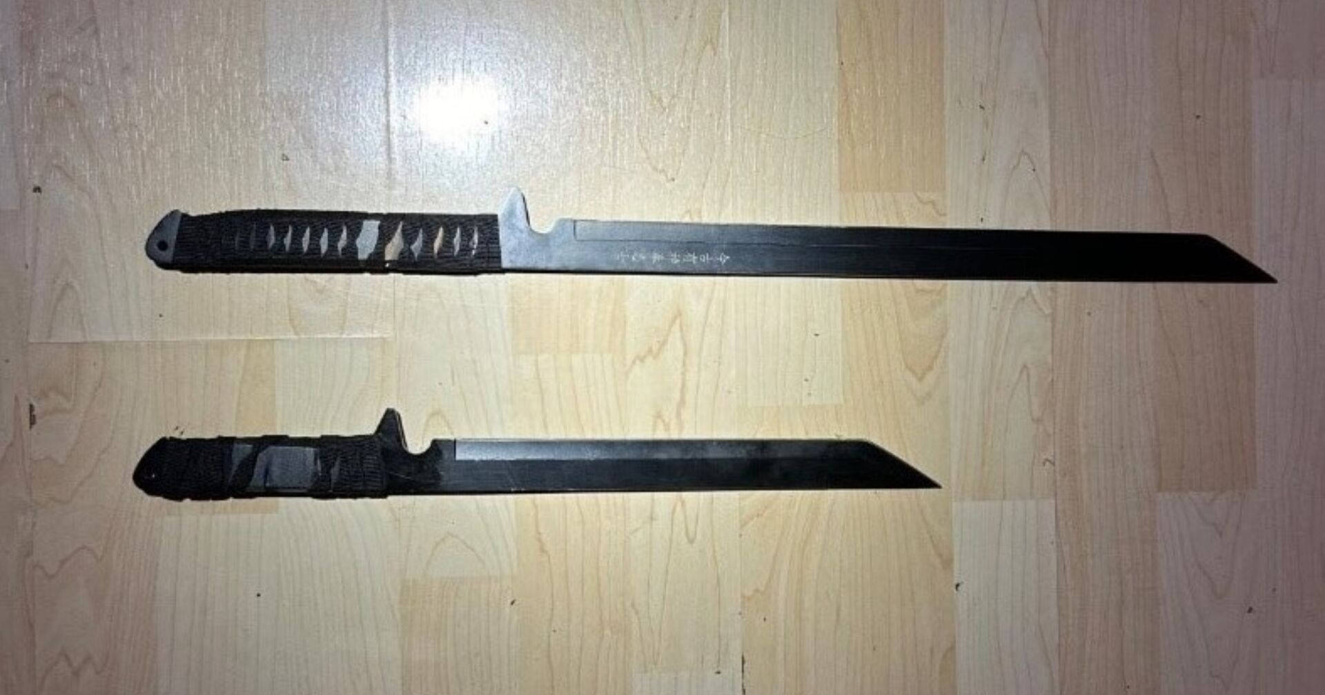 Zwei Macheten auf Holztisch liegend