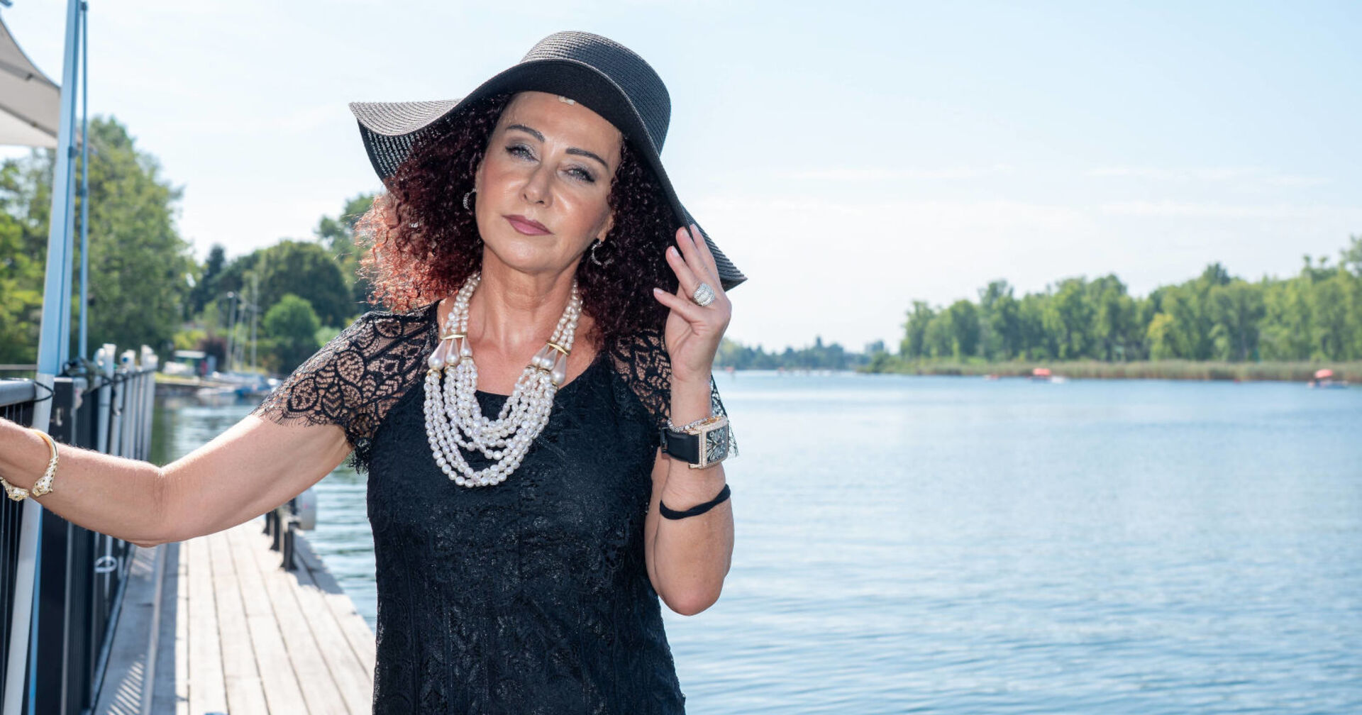 Eine Frau in schwarzem Outfit steht neben einem Fluss