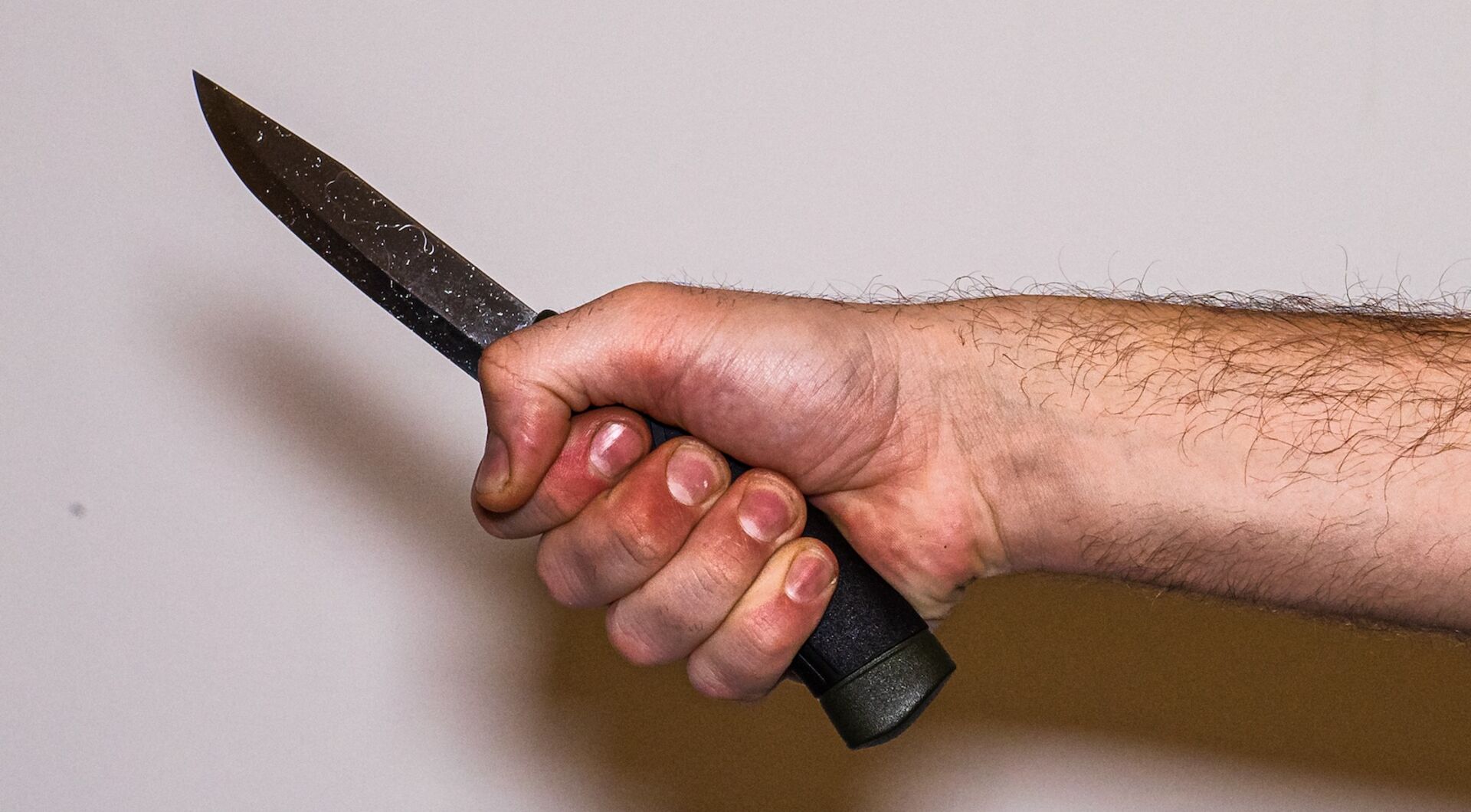 der Arm eines Mannes mit einem Küchenmesser in der Hand