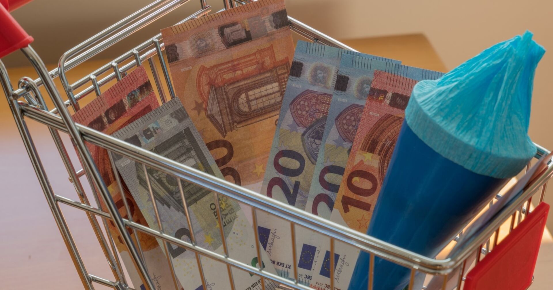 Einkaufswagen mit Geldscheinen und Schultüte gefüllt