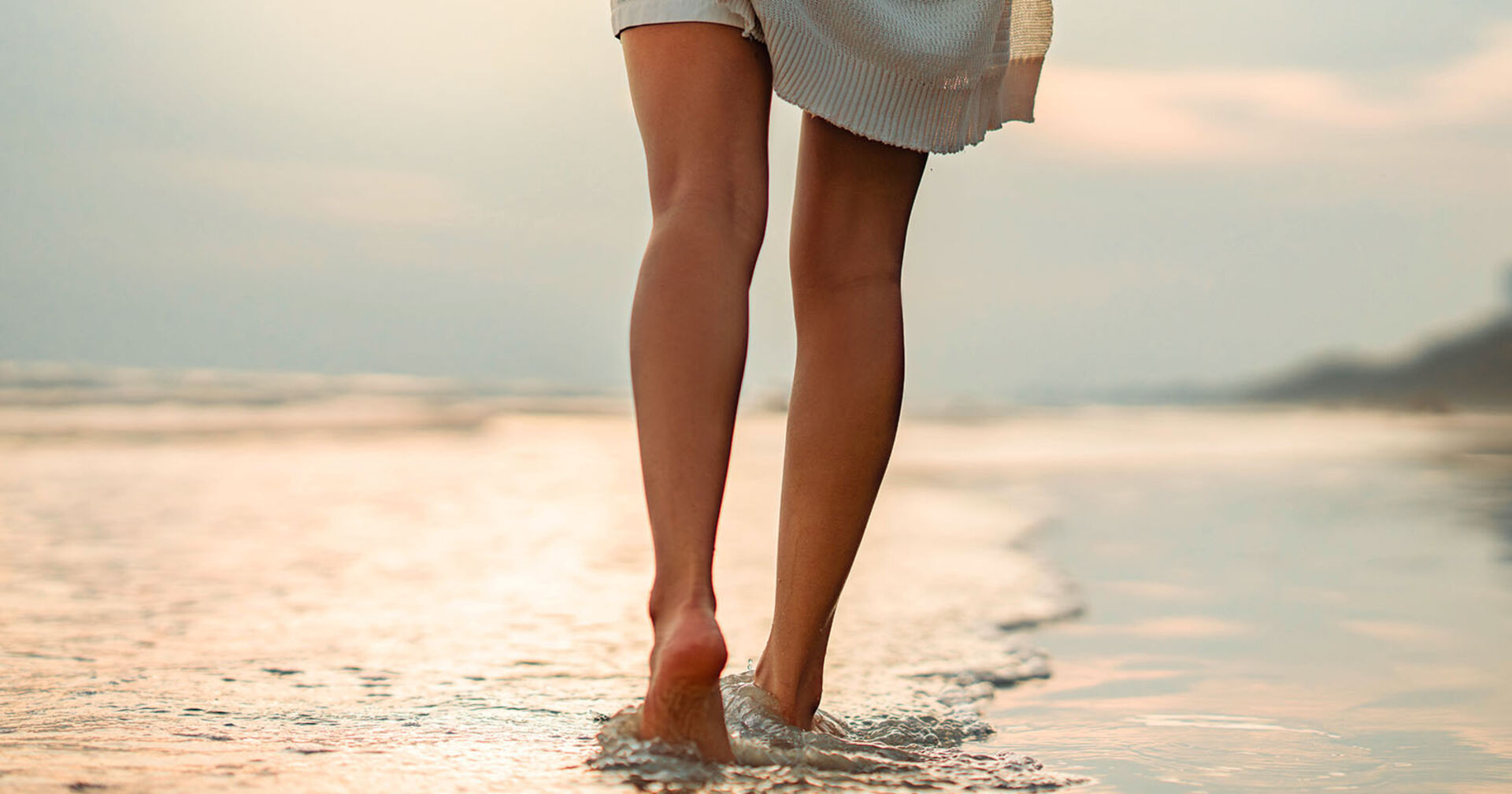 Frau geht barfuß durch den Sand | Credit: iStock.com/oatawa