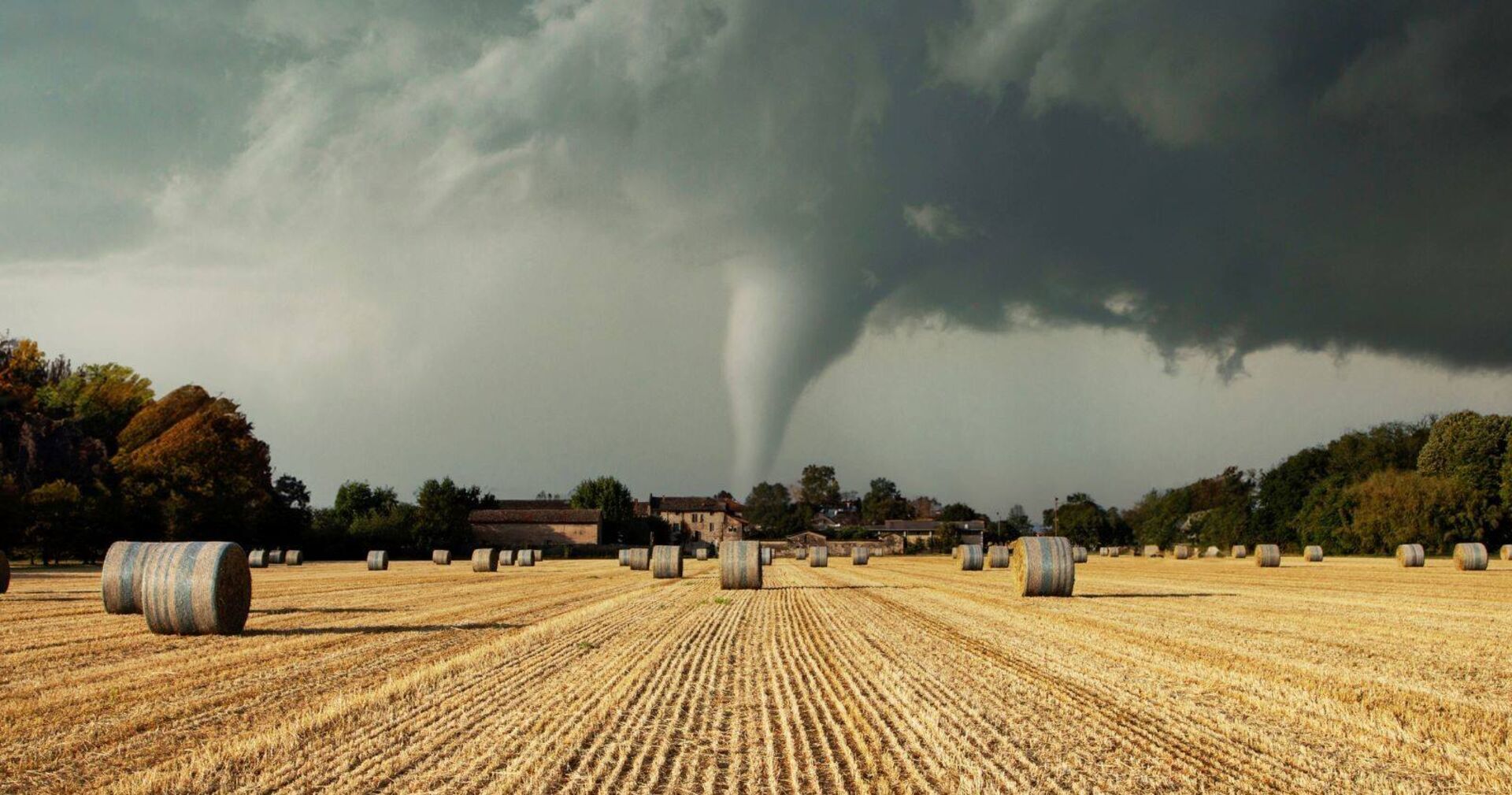Ein Tornado fegt über ein Feld mit Heuballen.
