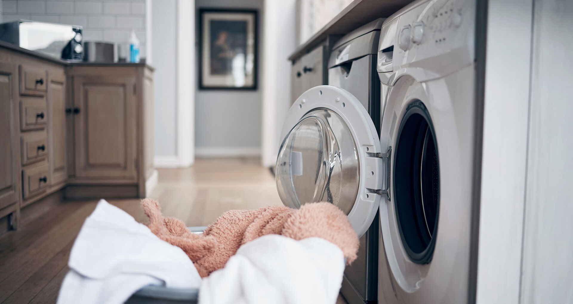 Wäschekorb steht vor einer Waschmaschine | Credit: iStock.com/PeopleImages