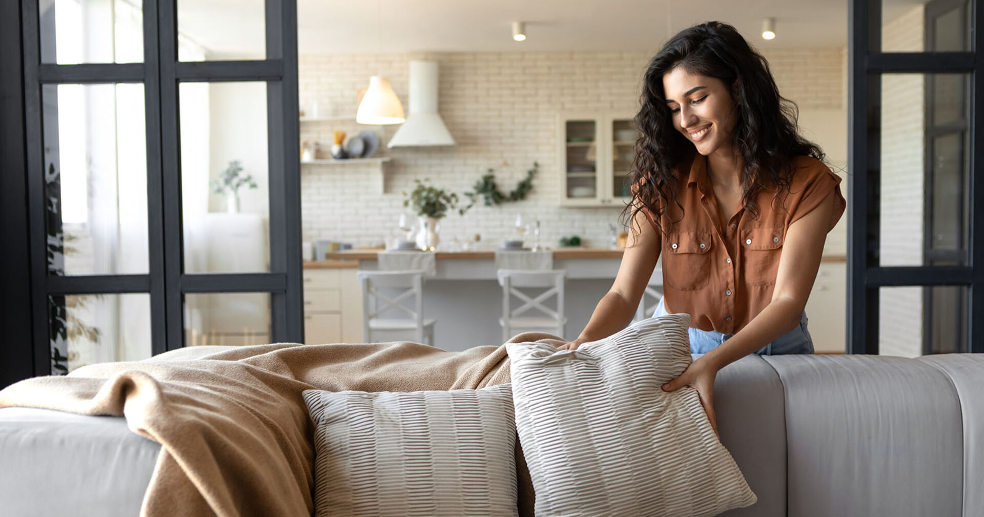 Frau richtet Kissen | Credit: iStock.com/Prostock-Studio