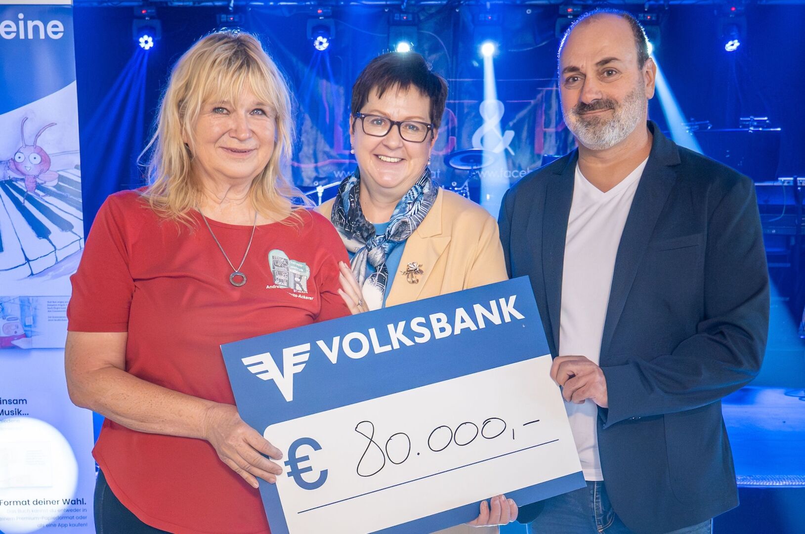 Drei Personen halten vergrößerten Scheck