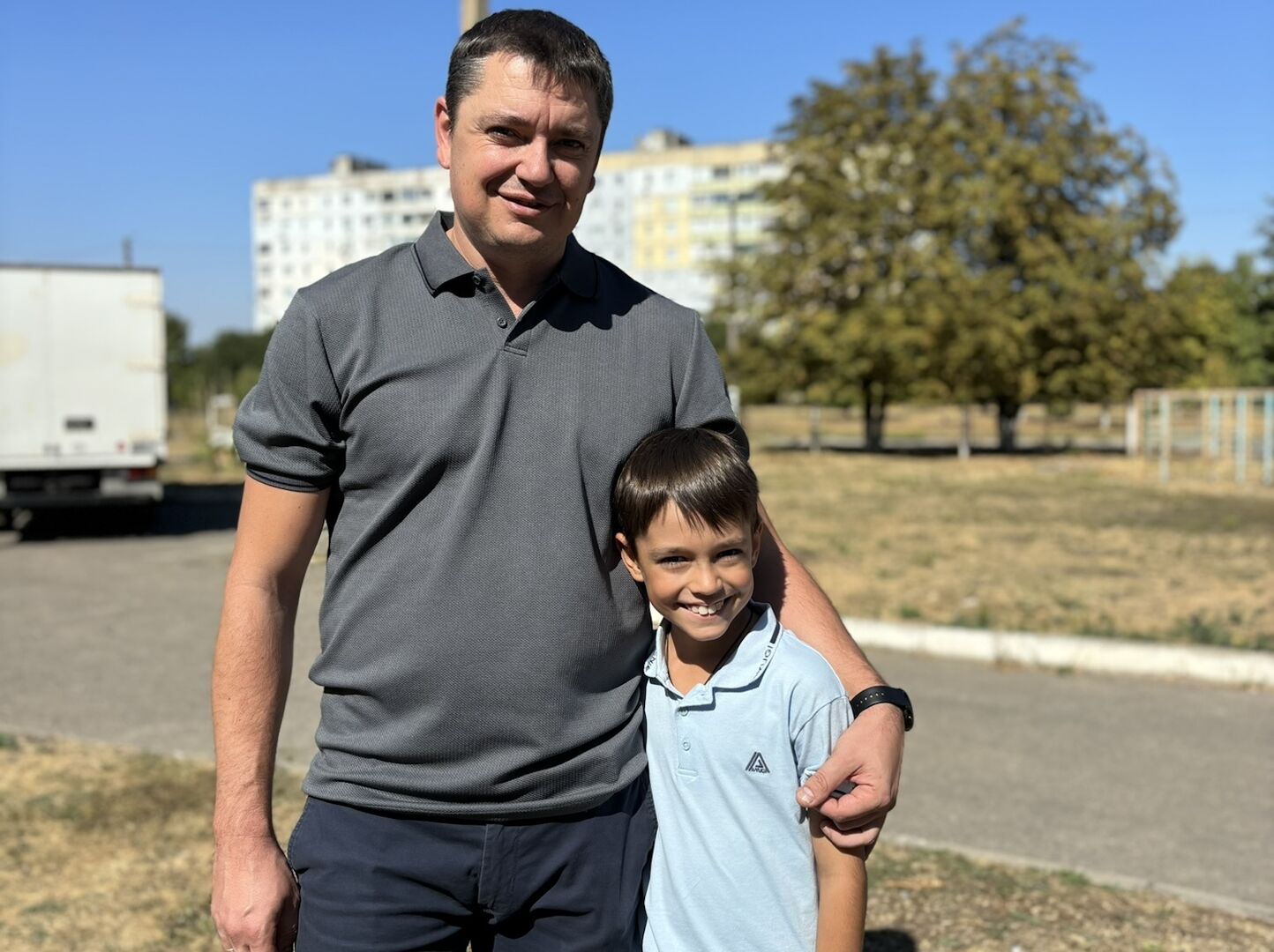 Vater hat den Arm um die Schulter des Sohnes gelegt