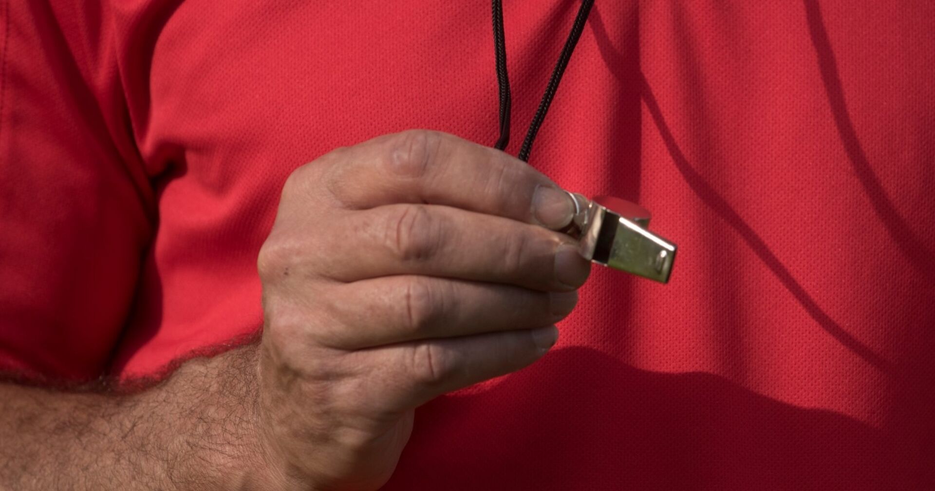 Schiedsrichter hält eine Pfeife in der Hand