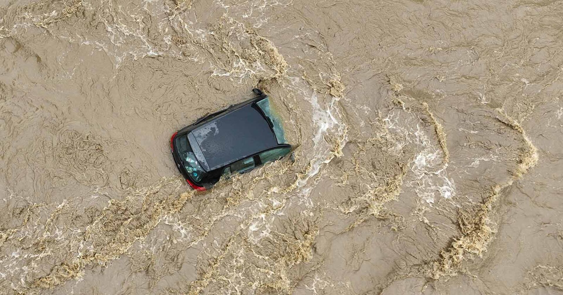 Luftaufnahme von Überschwemmungen im südlichen Polen. Ein Auto wird von den Fluten mitgerissen..
