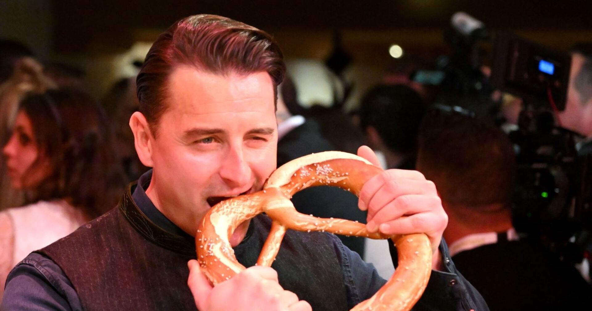 Andreas Gabalier beißt in eine Brezel.