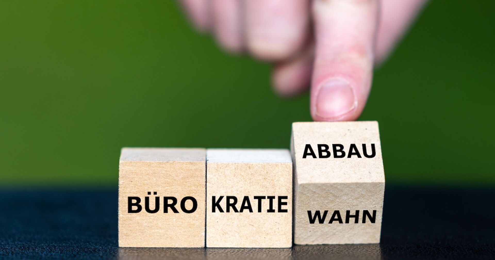 ein Finger kippt einen Holzwürfel