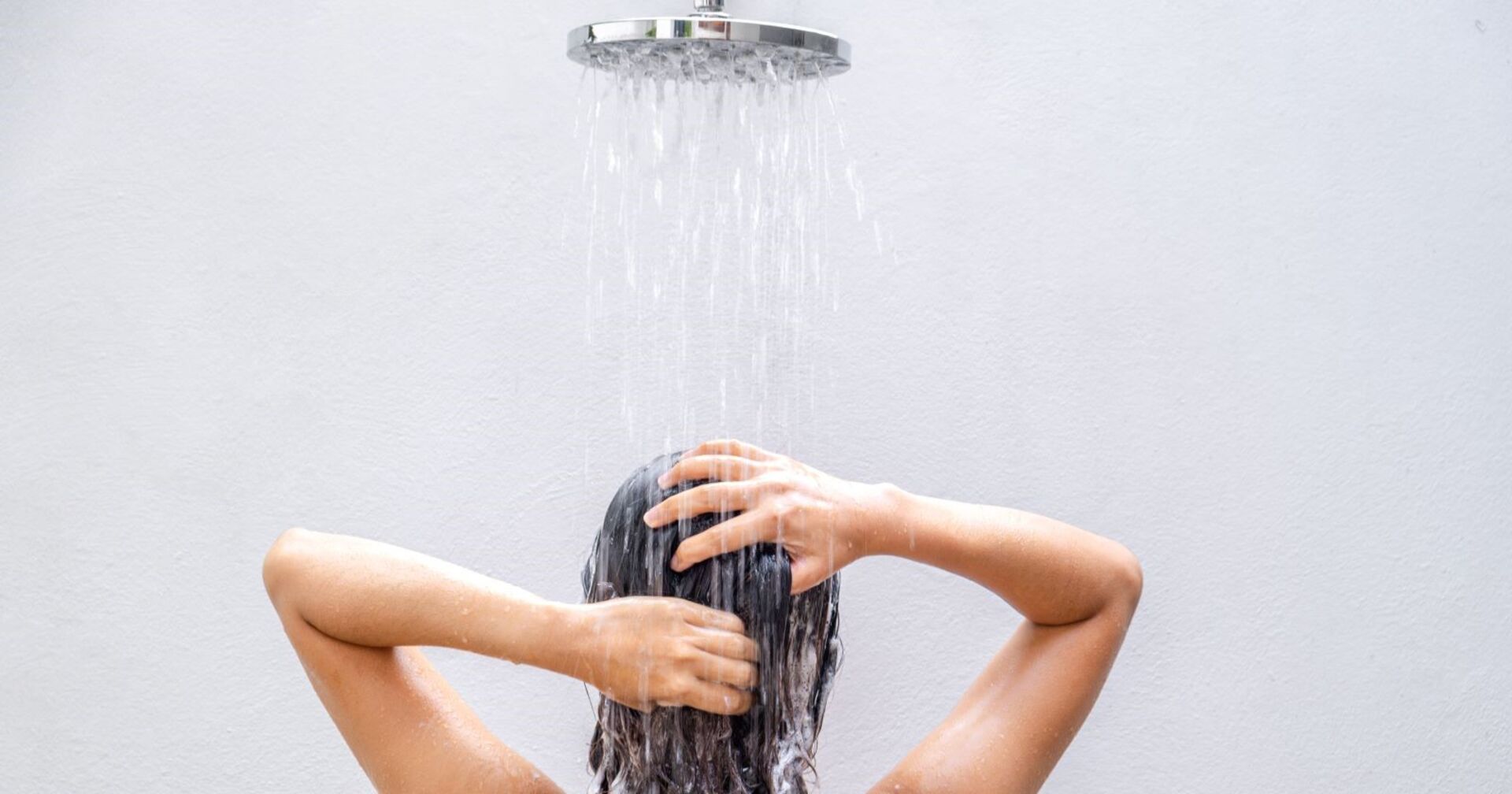 Frau in Dusche, welche sich die Haare wäscht