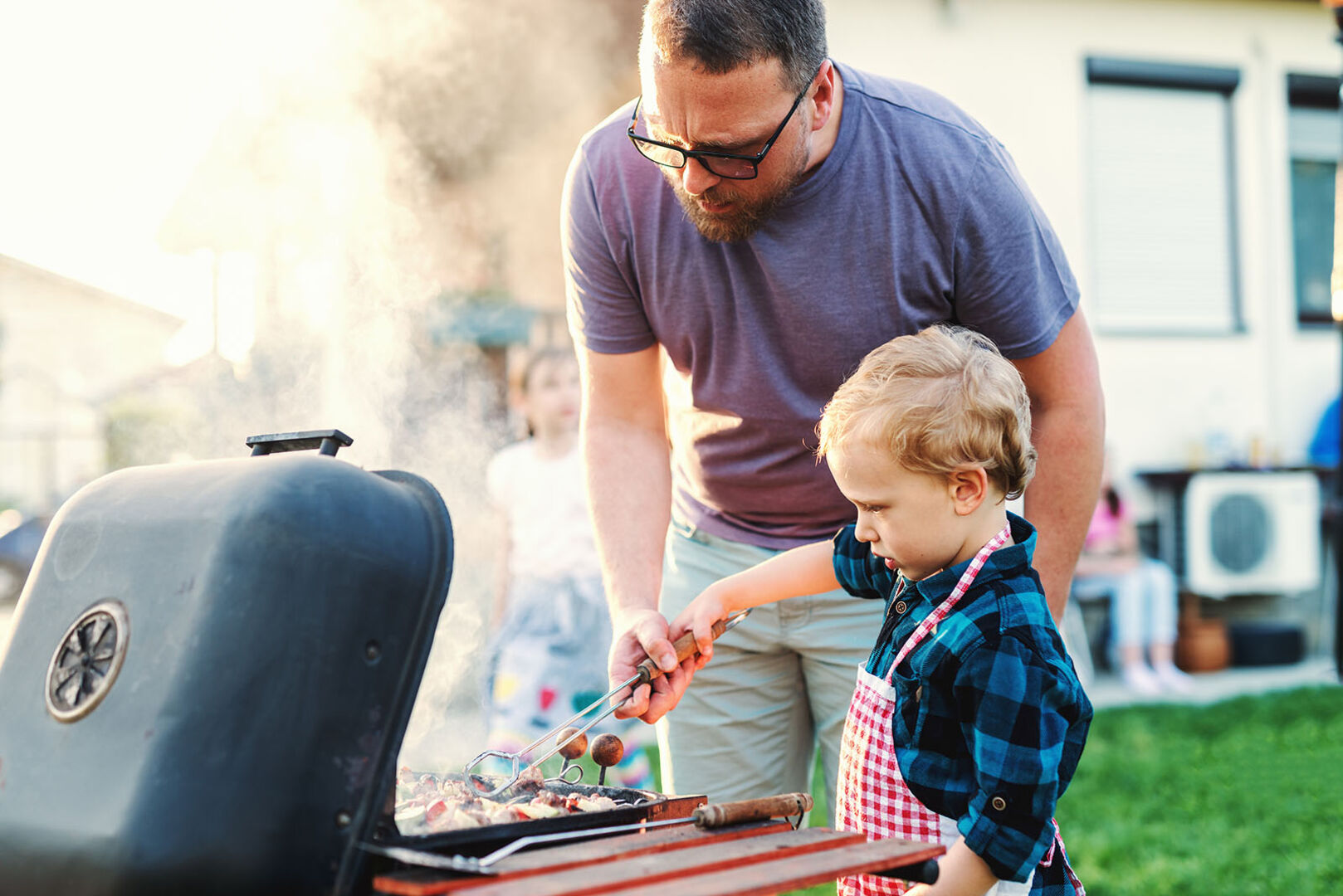Kind grillt mit Vater | Credit: iStock.com/dusanpetkovic