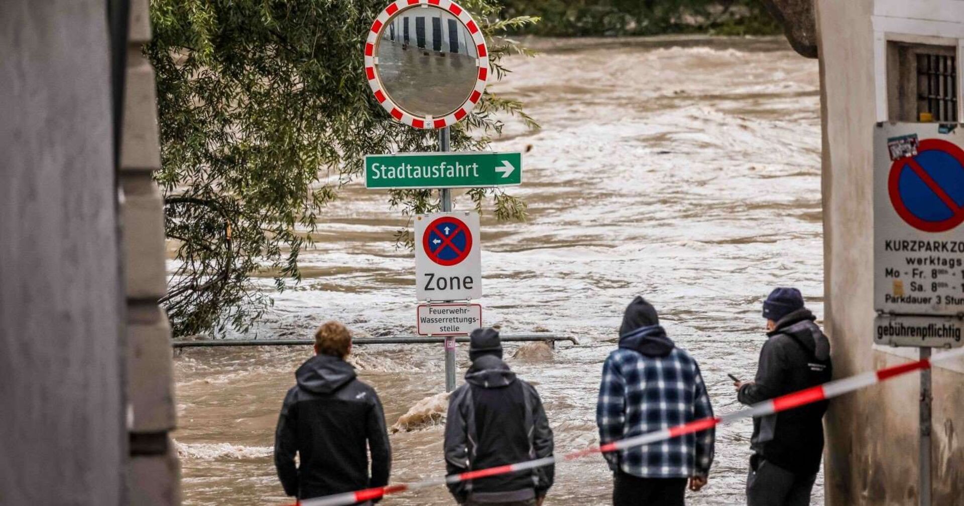 Vier Männer blicken auf eine überschwemmte Straße.