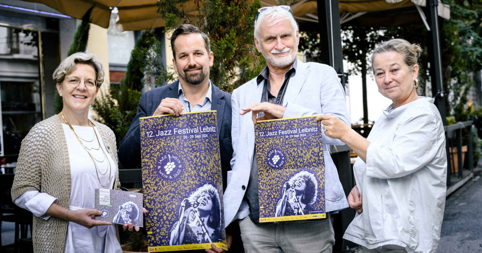 Zwei Männer und zwei Frauen halten Plakate hoch