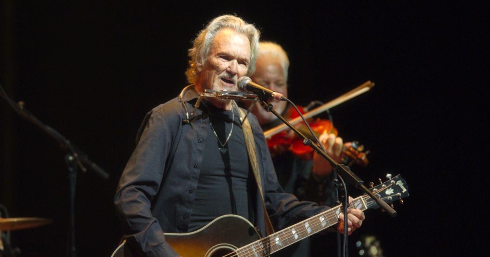 Kris Kristofferson mit Gitarre auf der Bühne.