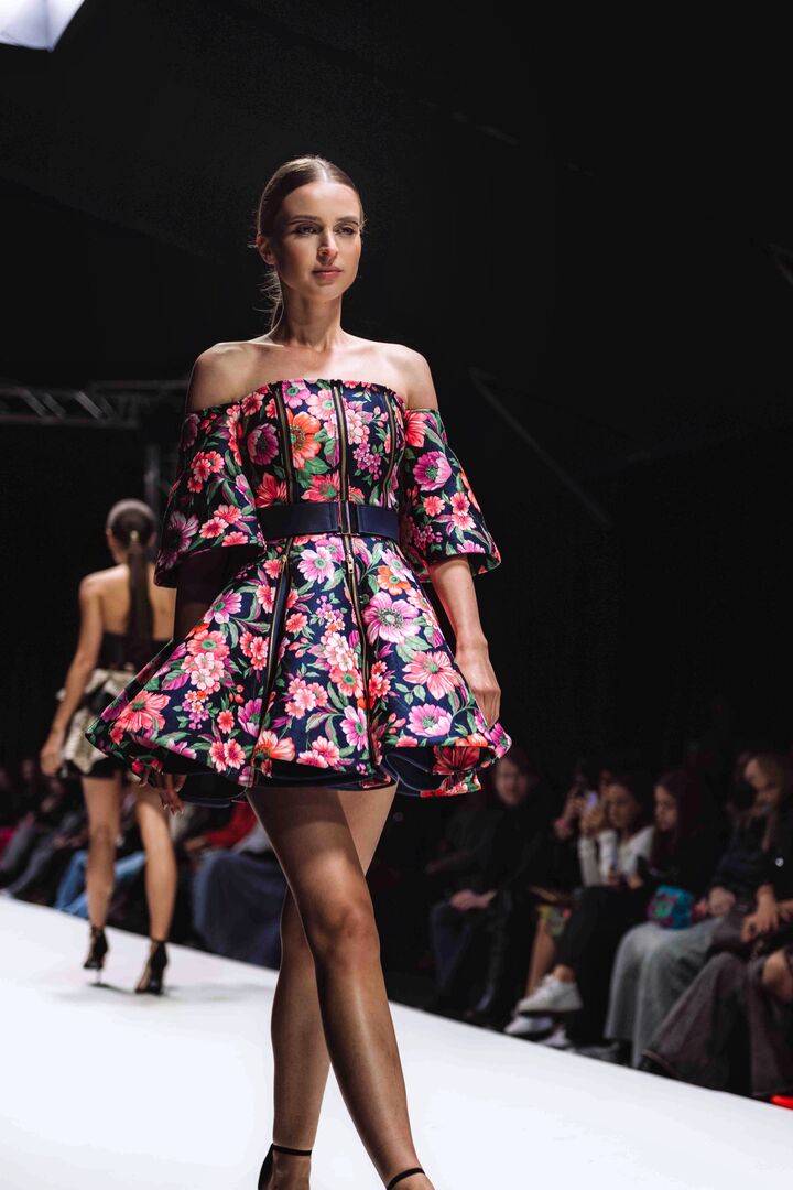 Eine Frau in einem kurzen Kleid mit Blumenmuster am Laufsteg