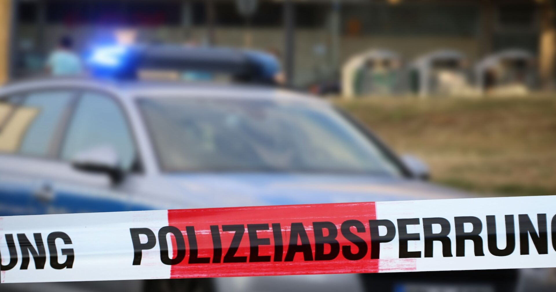 Ein Polizeiauto hinter einer rot-weißen Absperrung.