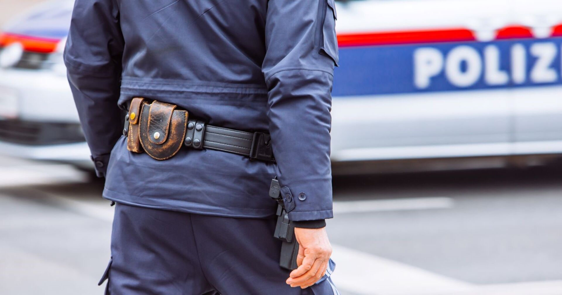 Polizist mit Munitonsgürtel geht auf Auto zu