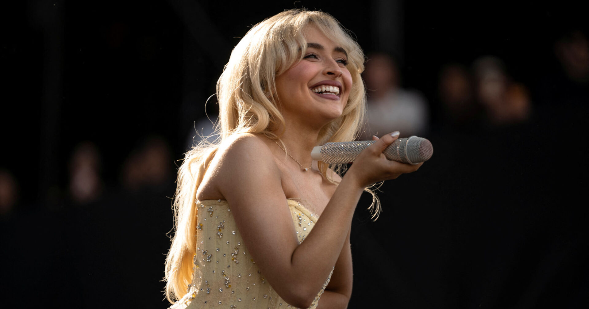 Blonde Sängerin lächelt und hält glitzerndes Mikrofon in der Hand