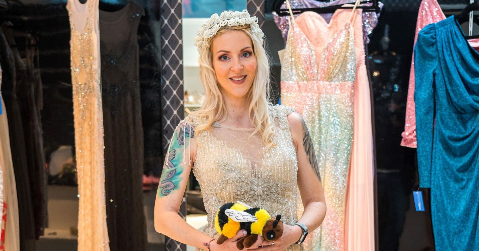 Simone Lugner in einem Kleid mit einer Stoff-Biene in den Händen.