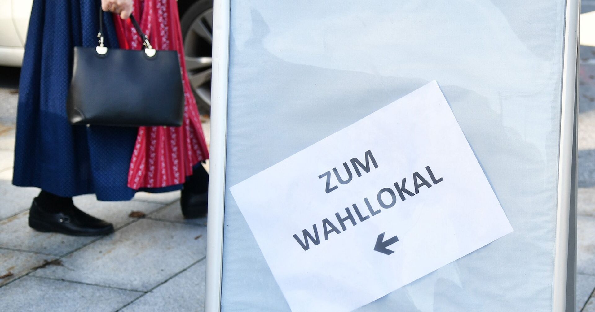 Eine Frau im Dirndl geht ins Wahllokal.
