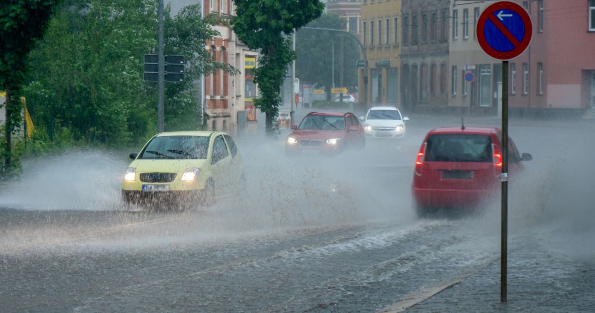 Starker Regen auf den Straßen, Autos fahren durch zentimeterhohes Wasser