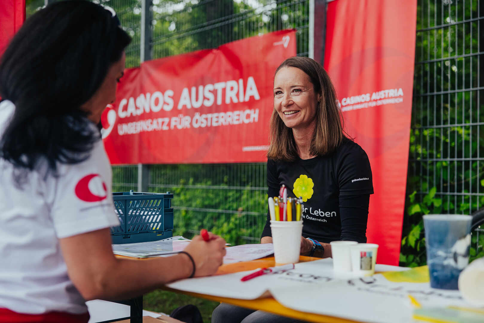 Junge Frau hinter einem Informationsstand im Freien | Credit: Casinos Austria