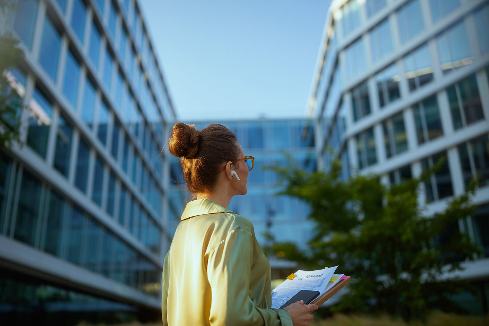 Junge Frau mit Block in der Hand vor einer modernen Wohnhausanlage | Credit: iStock.com/CentralITAlliance