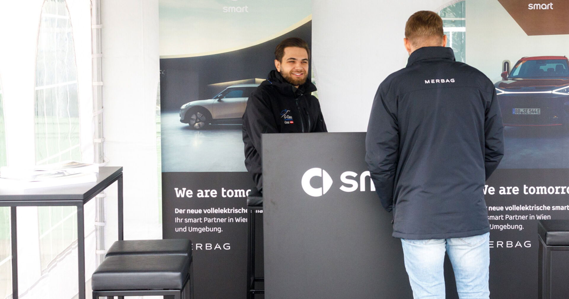 Zwei Männer bei einem Infostand | Credit: Weekend Magazin/Mika-Nikolas Mahringer