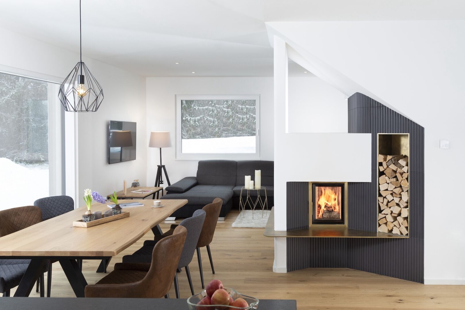 Helle Wohnküche mit großem Esstisch und grau-weißem Kachelofen