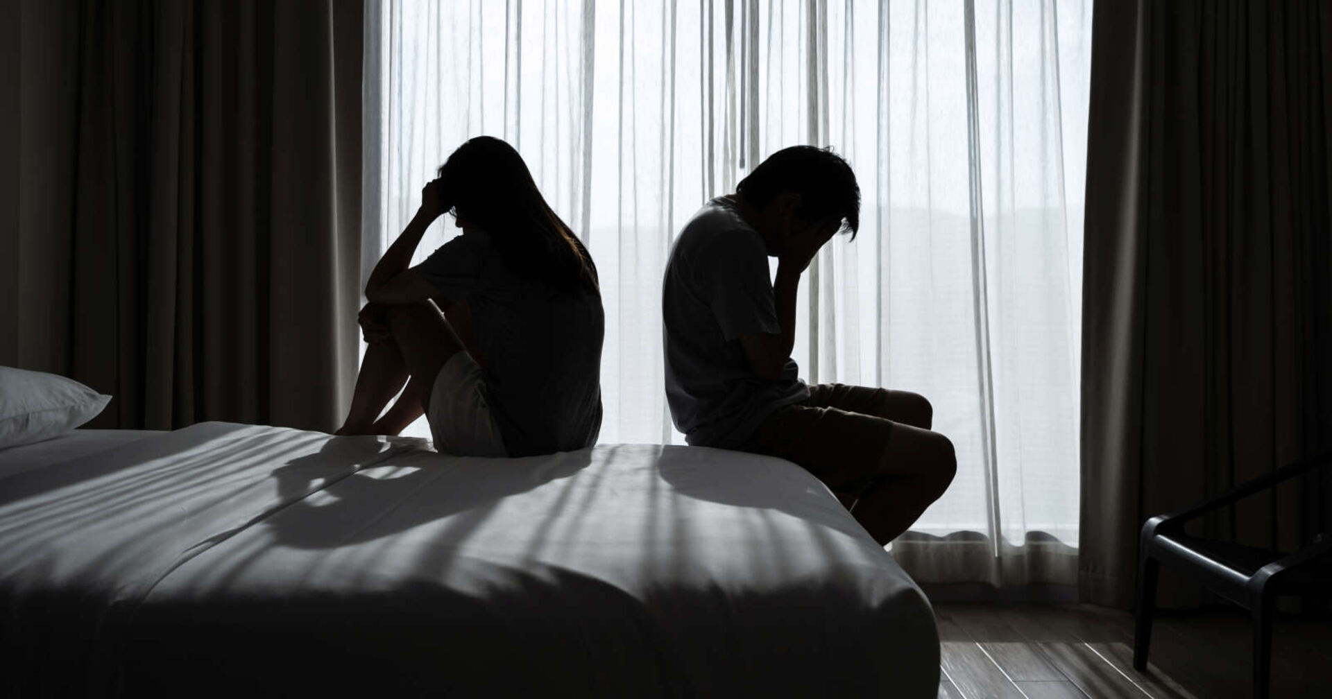 Ein trauriges Paar sitzt Rücken an Rücken.