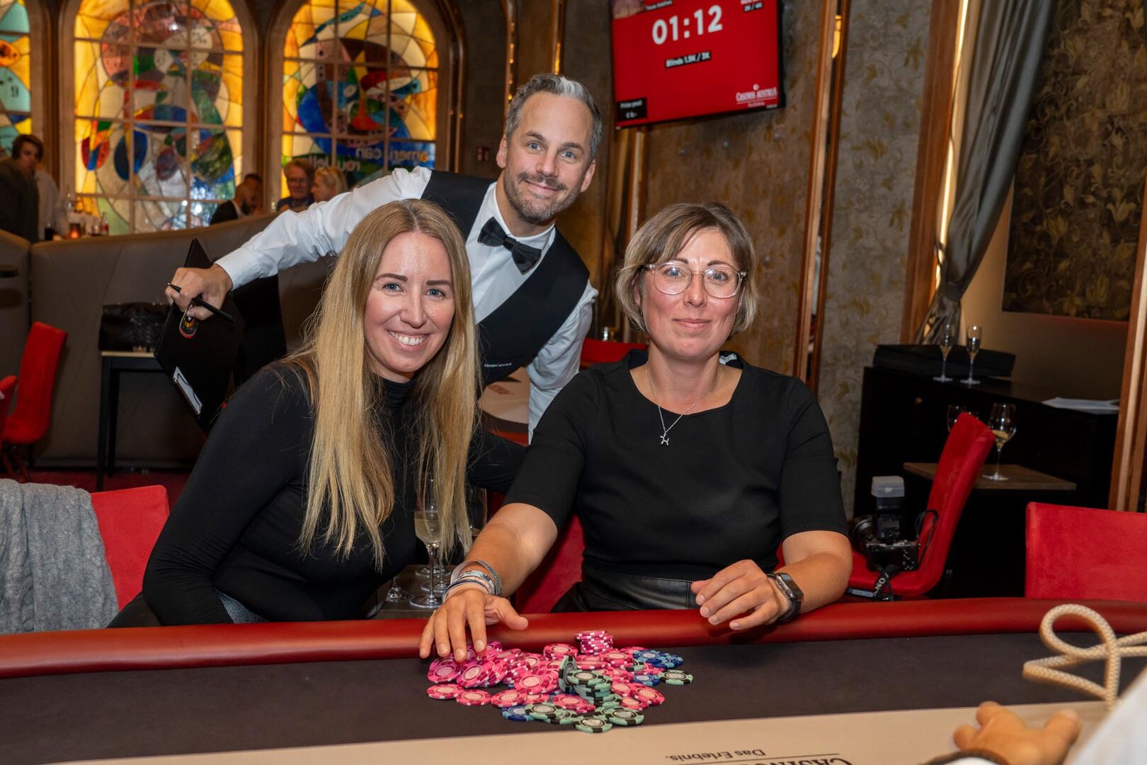 Zwei Frauen am Pokertisch, dahinter ist ein Mann